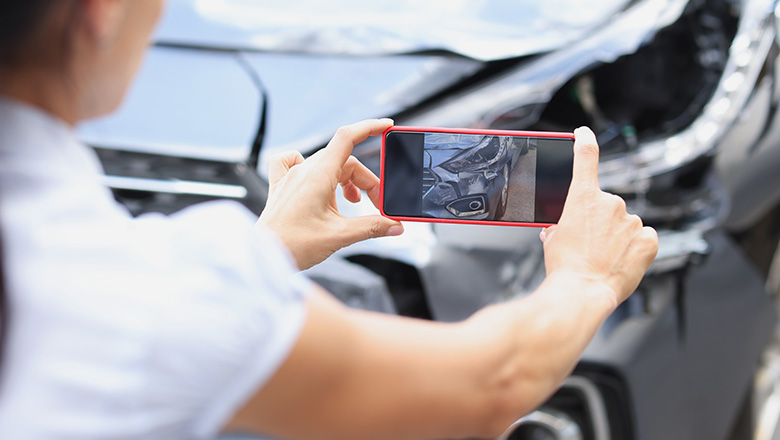 Individual taking a picture of their wrecked vehicle.