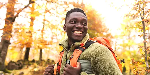 a young African American man on a hike with a backpack through beautiful nature on a beautiful autumn day