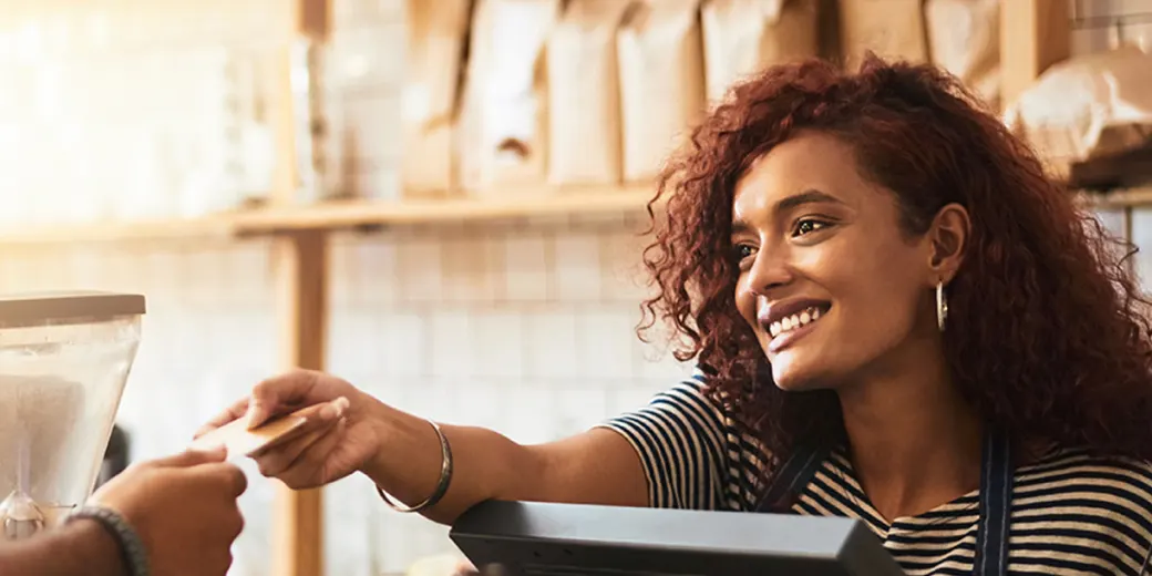 Young woman handing debit card back to customer