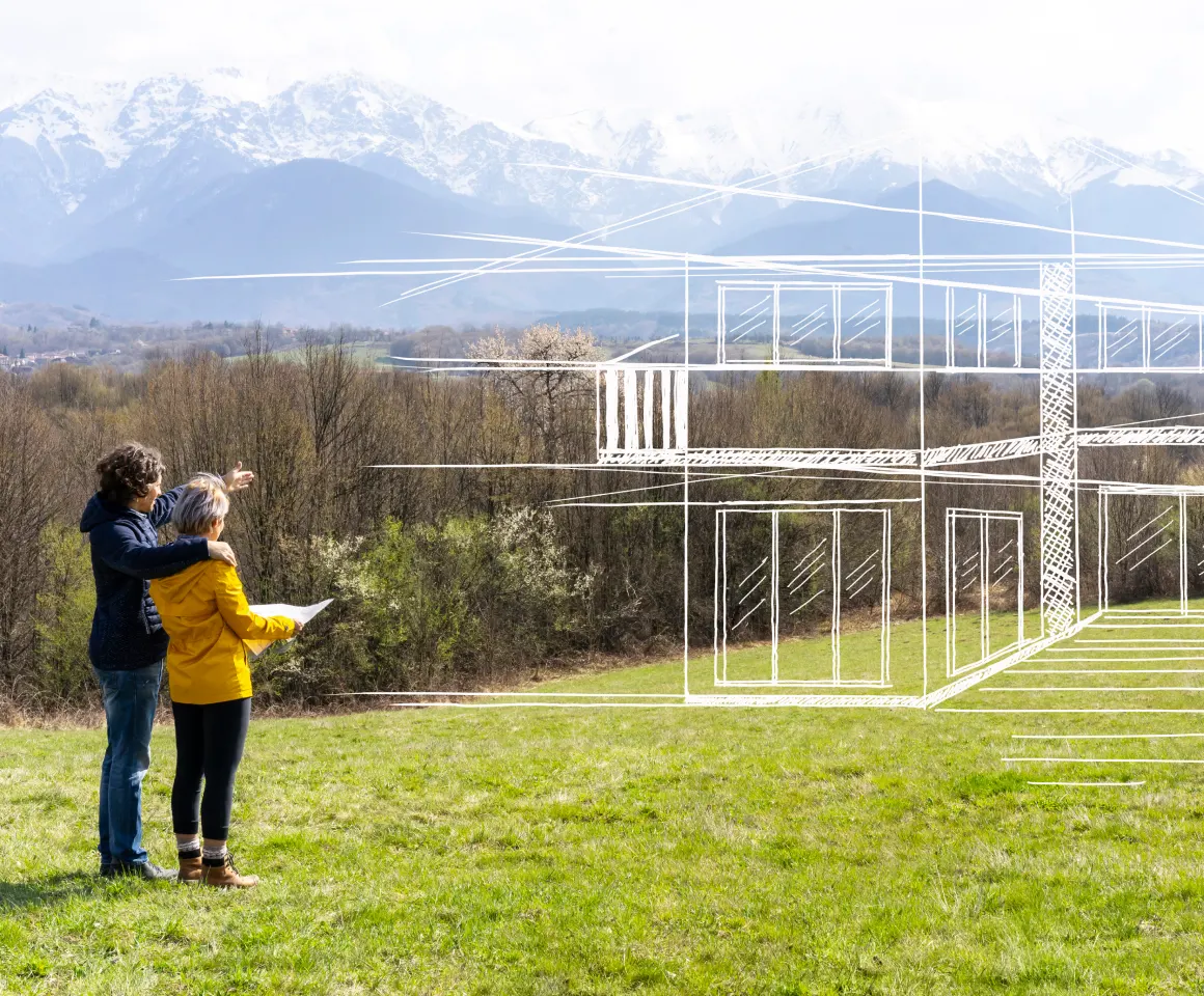 Couple discussing potential homes in an empty lot with blueprints drawn over it